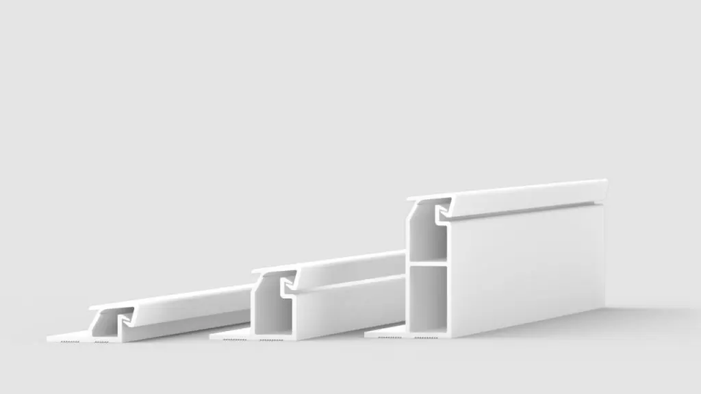 Three white, elongated plastic or metal profiles of varying sizes are arranged in a row on a light gray background, each featuring a hollow rectangular and angular cross-section.