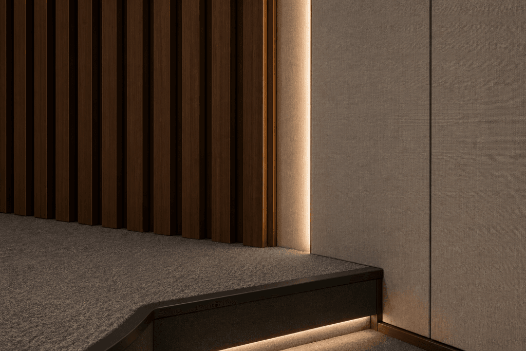 A modern interior corner with vertical wooden slats on one wall, textured fabric panels on the other, and soft accent lighting illuminating the joint above a carpeted raised platform.
