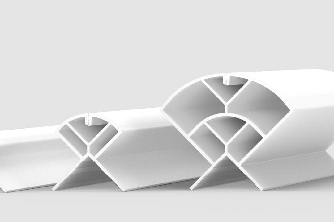 Three white, geometric, hollow plastic profiles with triangular and semicircular sections are arranged in a row on a light gray background, each progressively larger from left to right.