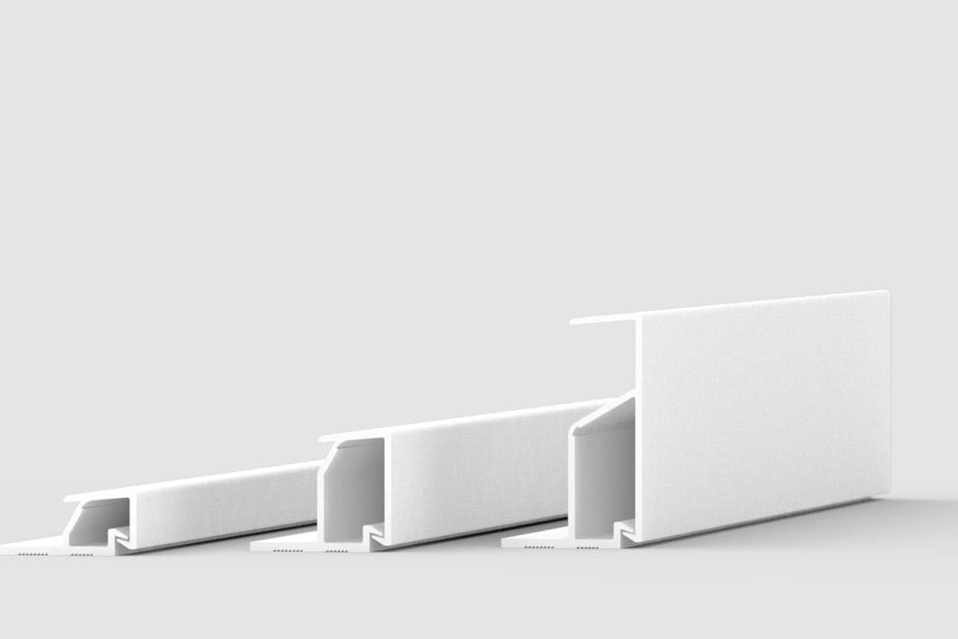 Three white, rectangular, L-shaped plastic or metal profiles of varying heights are arranged side by side on a plain, light gray background.