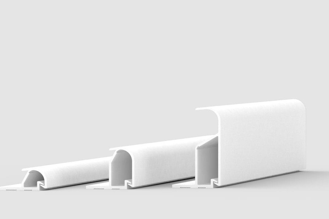 Three white, L-shaped plastic or metal profiles of varying sizes are arranged in a row on a light grey background, each standing upright and gradually increasing in height and width from left to right.
